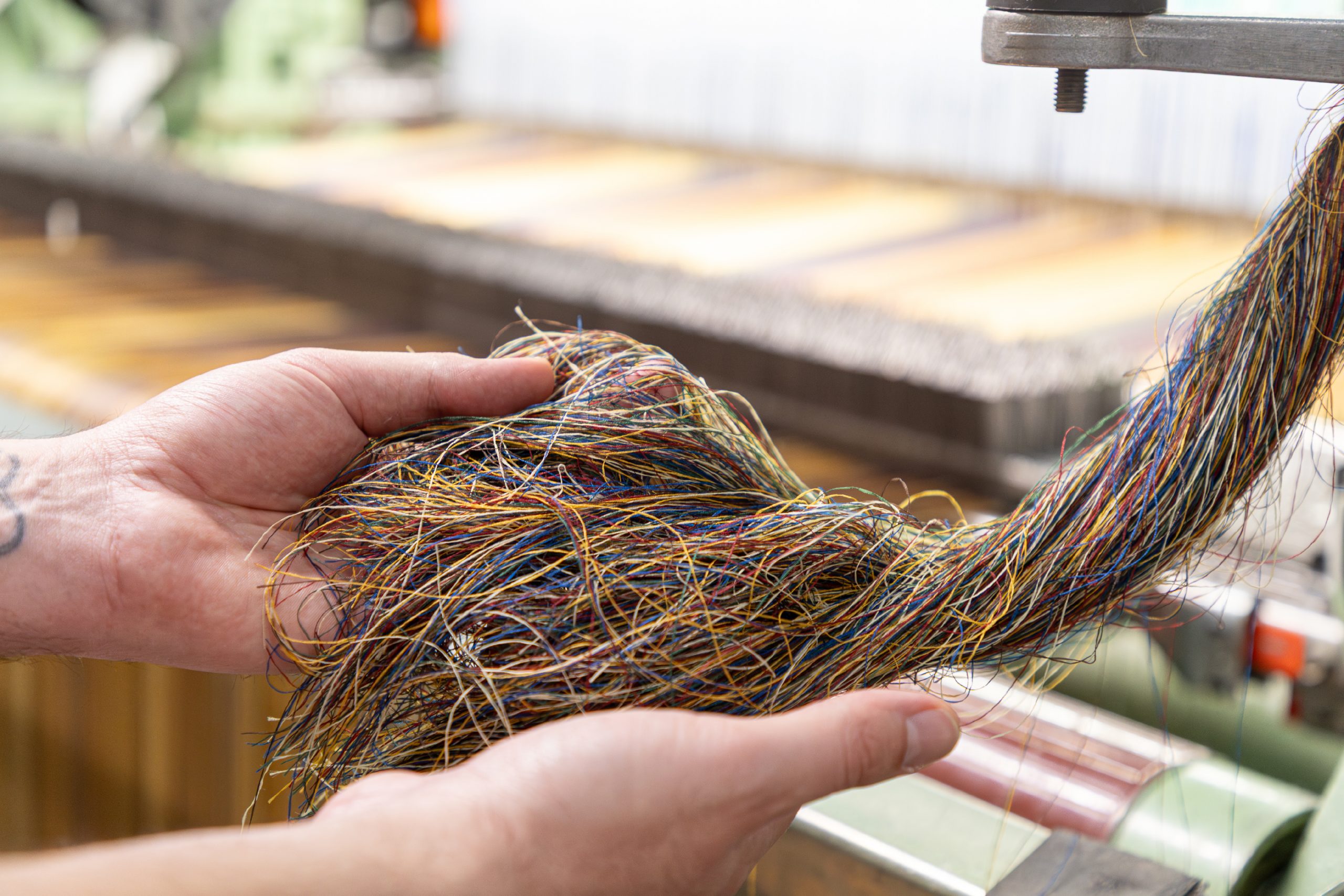 Sostenibilità tessile: l'immagine rappresenta dei fili tenuti fra le mani durante una fase di lavorazione